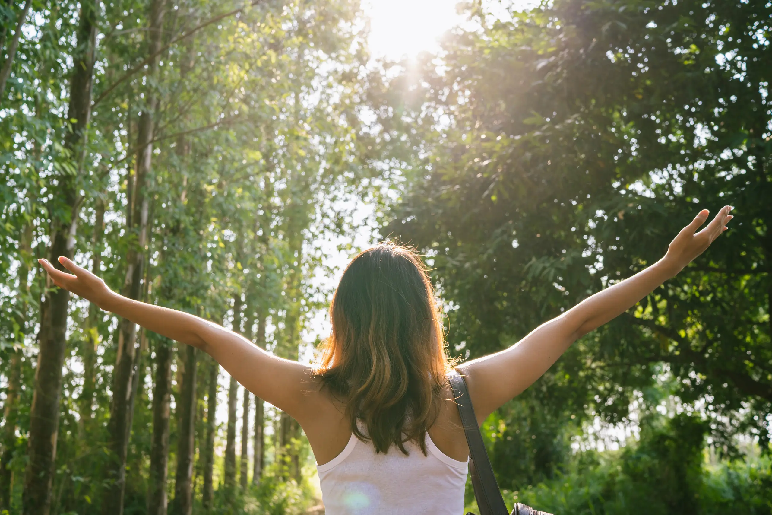 happy young woman-traveler with backpack walking forest